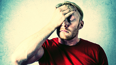 Ein Mann im roten Hemd, der sein Gesicht bedeckt.